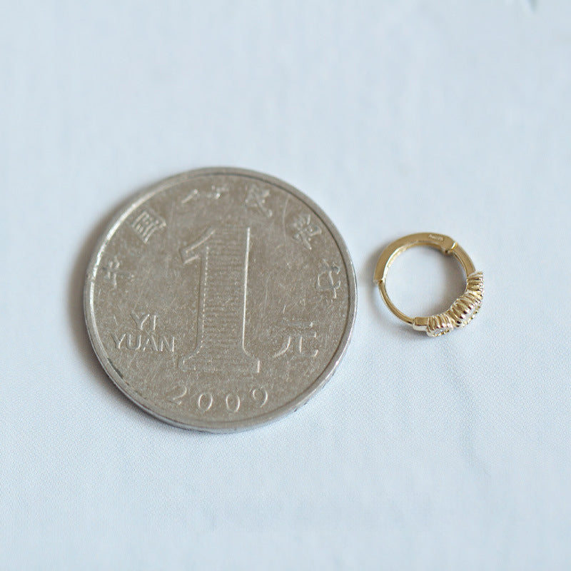 Size comparison of the gold-plated zirconia huggie earring next to a coin.