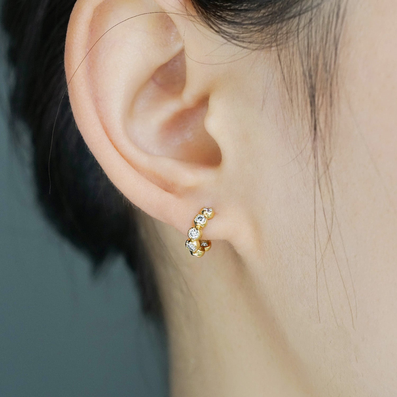 A model wearing the 925 sterling silver bezel-set CZ hoop earring to show its elegant look.