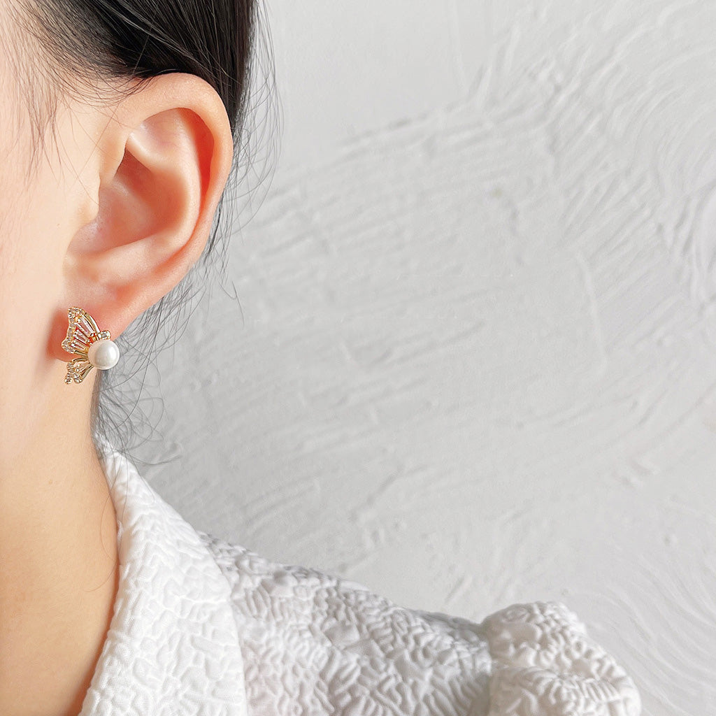 A woman wearing the gold butterfly stud earring with pearl and zircon