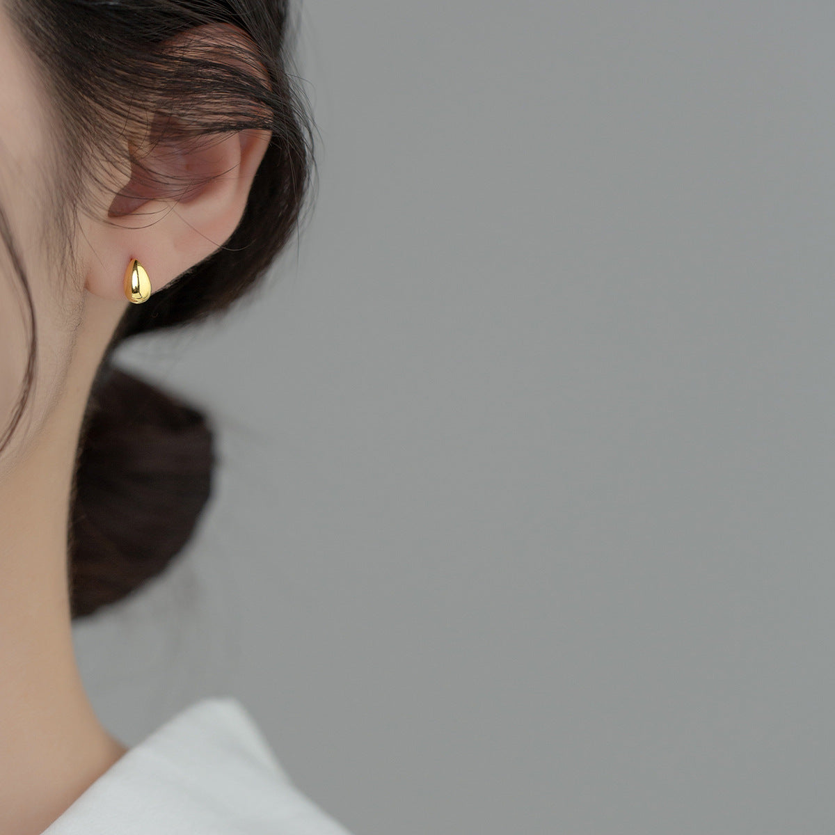 Model wearing the gold water-drop stud earrings