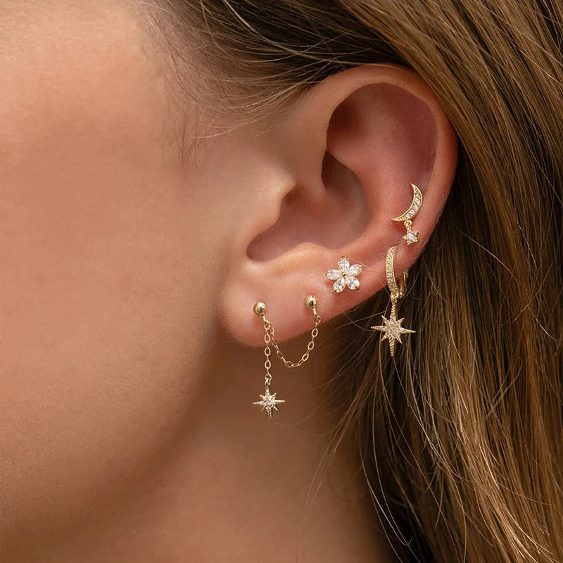 Model wearing the gold star pendant earrings as part of a stylish ear stack.