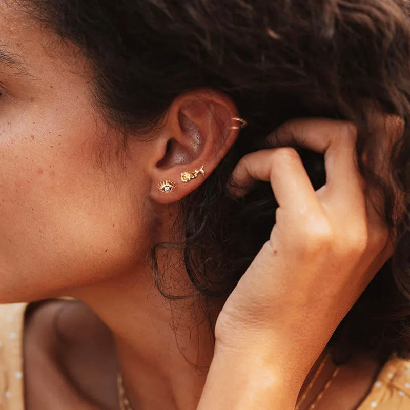 Model wearing the gold eye design zircon stud earrings as part of an ear stack