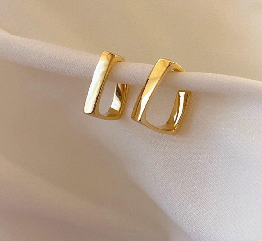Wide square hoop earrings displayed on white fabric