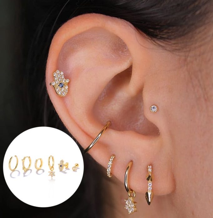A model's ear adorned with multiple gold huggie earrings from the set, showcasing a trendy layered style.