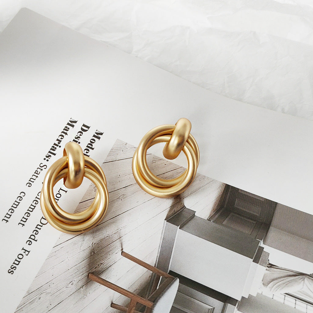 Detailed product photo of the matte gold geometric knot earrings