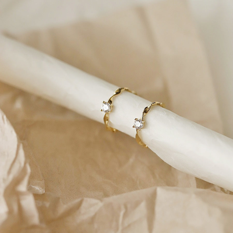 A pair of elegant gold huggie earrings with clear zircon gemstones