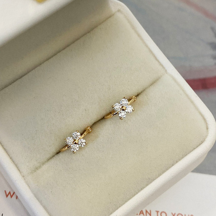 A pair of 18K gold-plated four-leaf clover earrings with zircon stones in a display box.