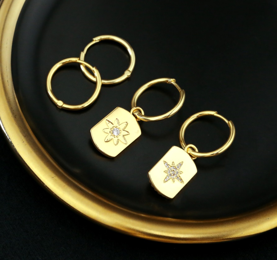 Detailed view of the Sunburst Huggie Earrings with flower-like pendants
