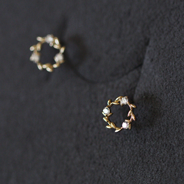 Detailed view of the gold wreath stud earrings' leaf pattern and gemstones
