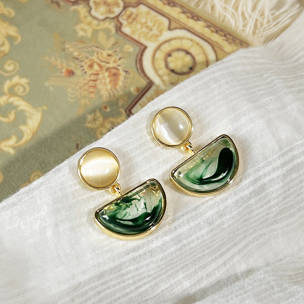 A stylish pair of drop earrings from the set, featuring a pearl-like top and green marbled detail.