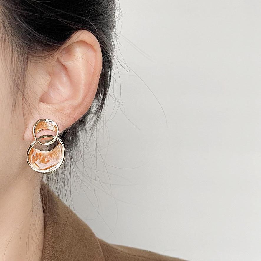 A pair of gold-plated earrings with a unique two-circle design and marbled camel enamel.