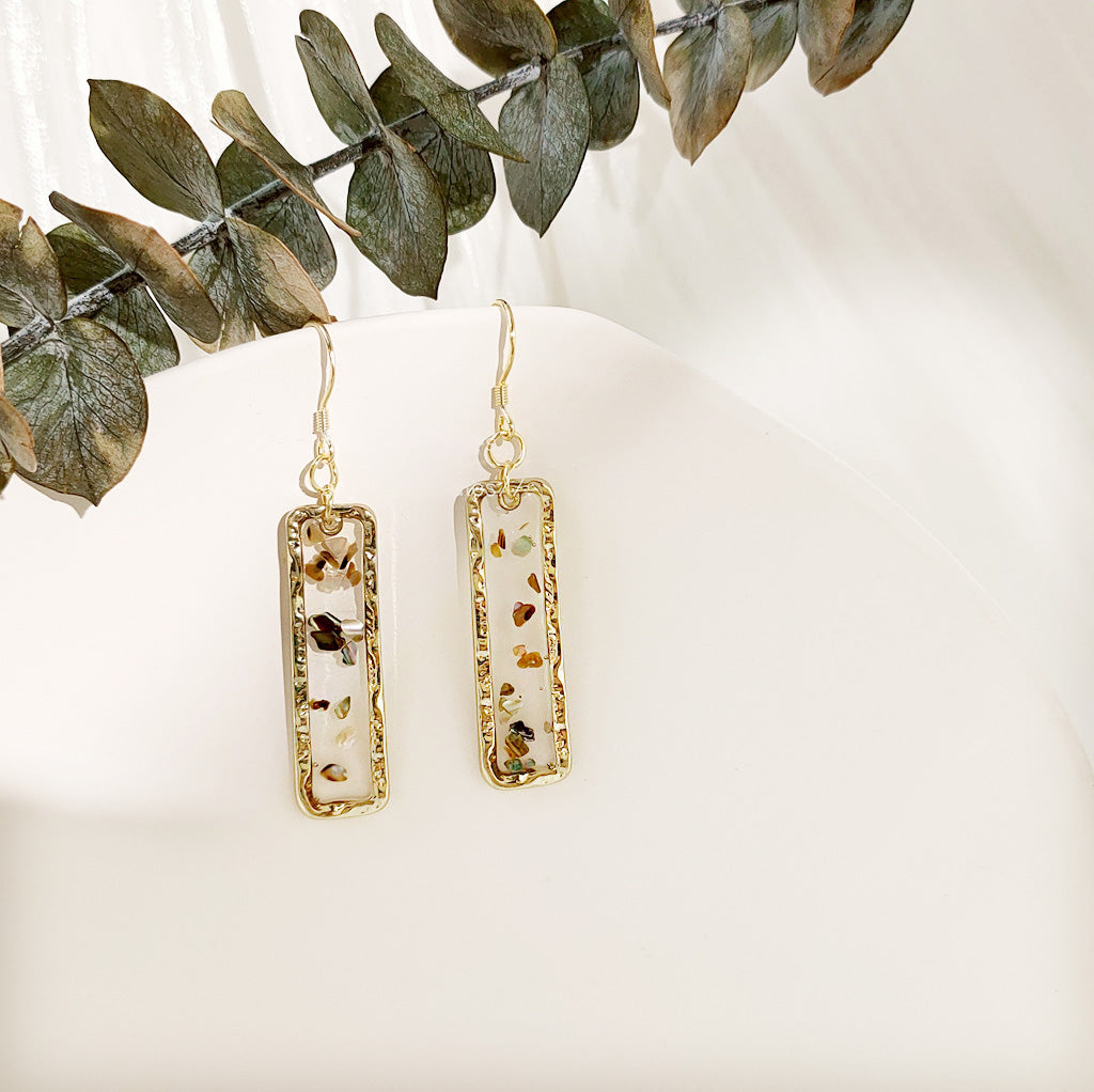 Detailed view of the resin and shell inclusions in the geometric earrings