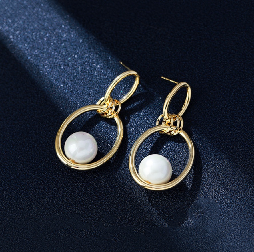 Close-up view of the gold plating and white pearl on the earrings