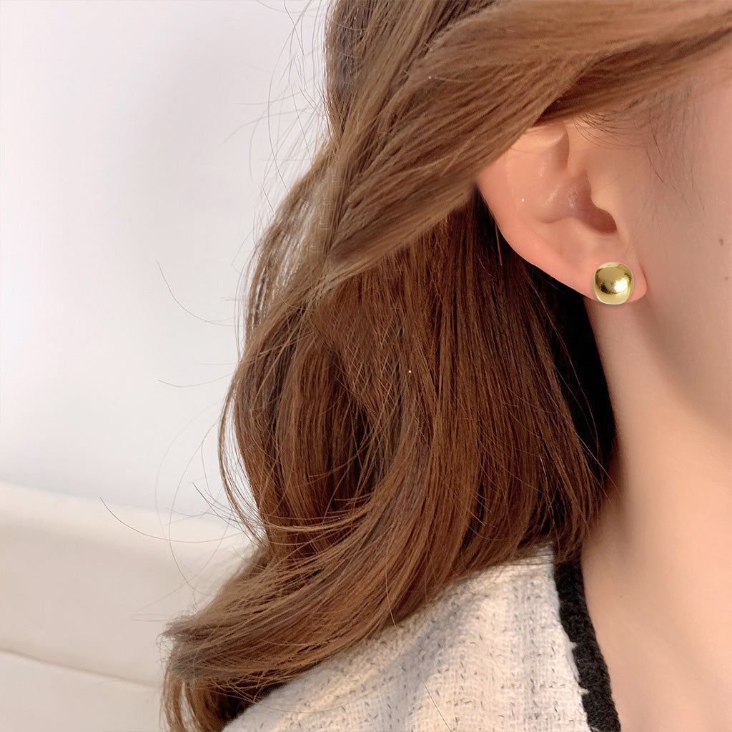 A woman models the simple gold pea button stud earrings, highlighting their elegant look.