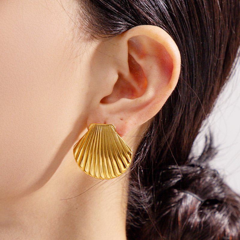 A woman wearing the gold chunky shell stud earring, showing its size and style.