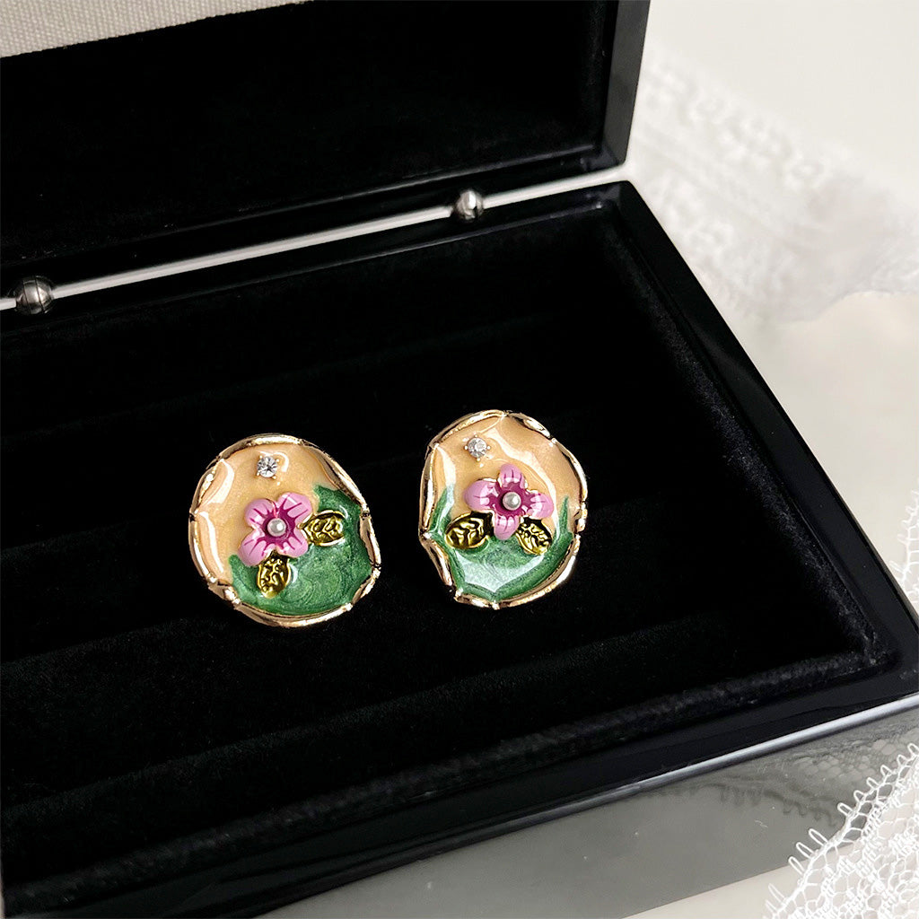 A set of five pairs of floral enamel earrings displayed in a presentation box
