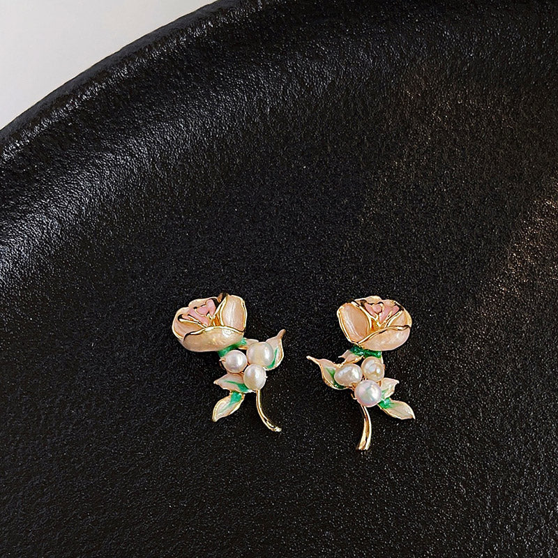 Detailed view of the gold floral earrings with pink enamel and pearl