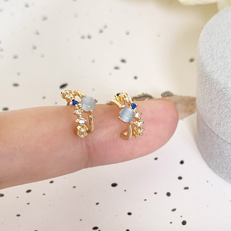 A pair of gold floral-designed earrings from the set, featuring delicate white and blue stones.