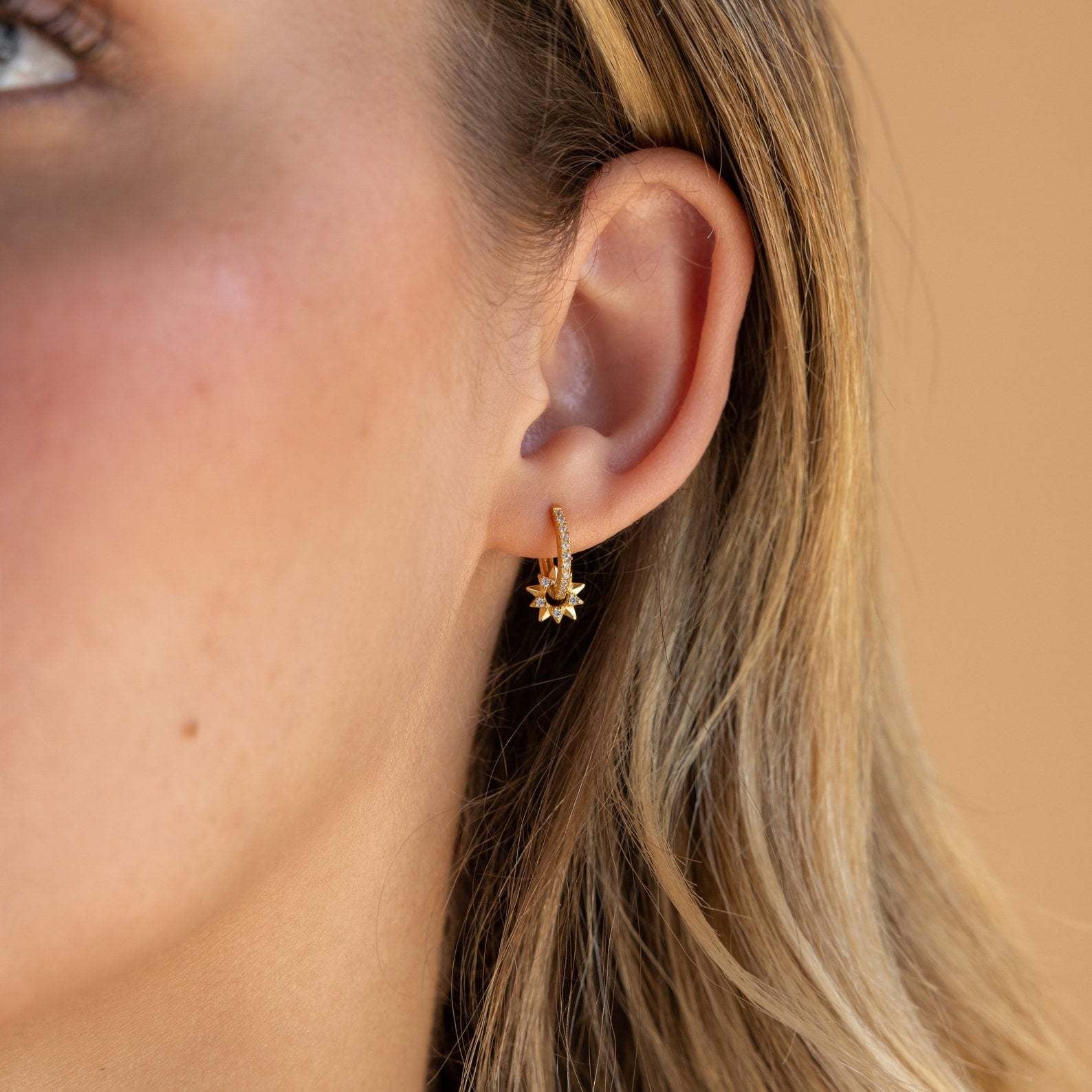 A close-up of the S925 gold-plated star huggie earring being worn, highlighting its sparkle.