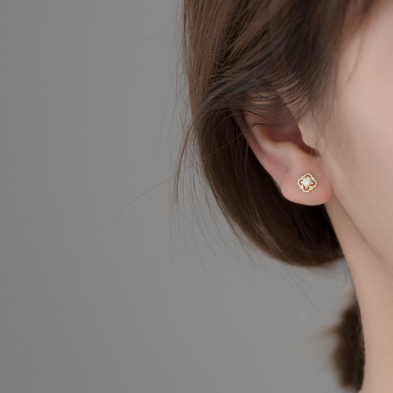 A model showcasing the elegant fit of a flower-shaped gold opal stud earring.
