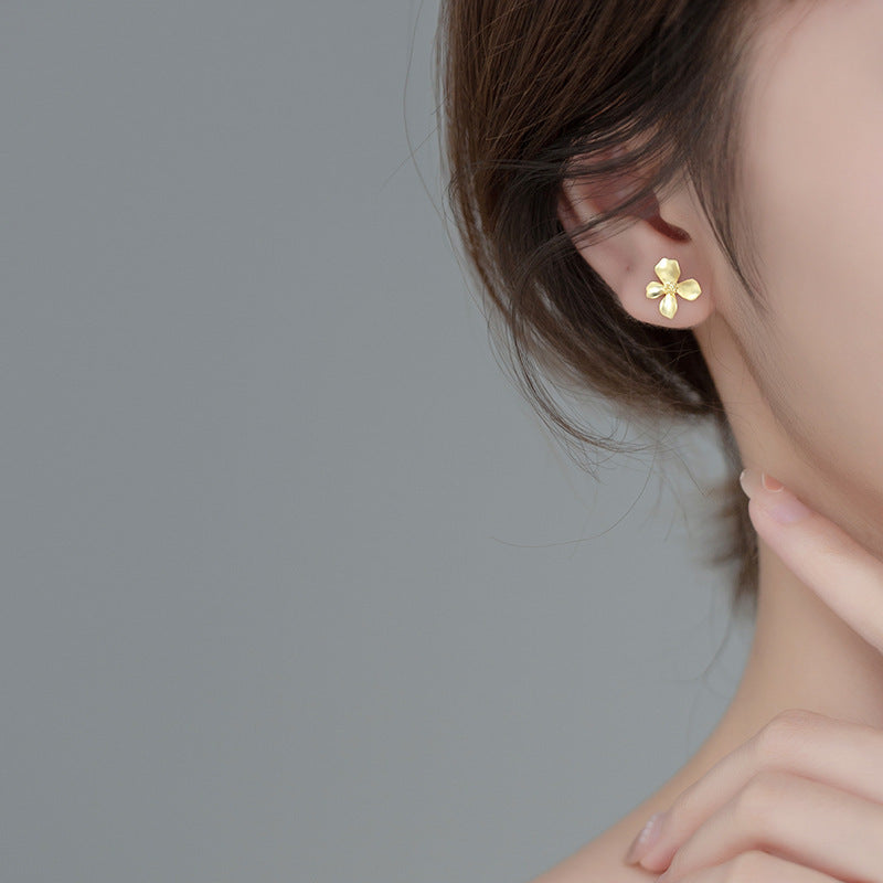 A model showcasing the delicate gold flower stud earring