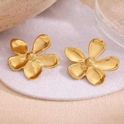 A pair of 18K gold plated daisy flower earrings on a white surface
