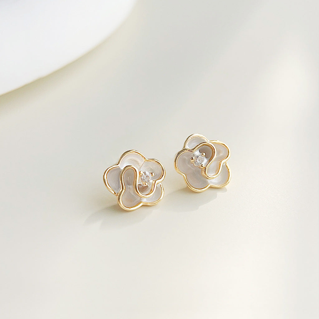 A pair of 14k gold-plated flower earrings with white enamel and zircon centers.