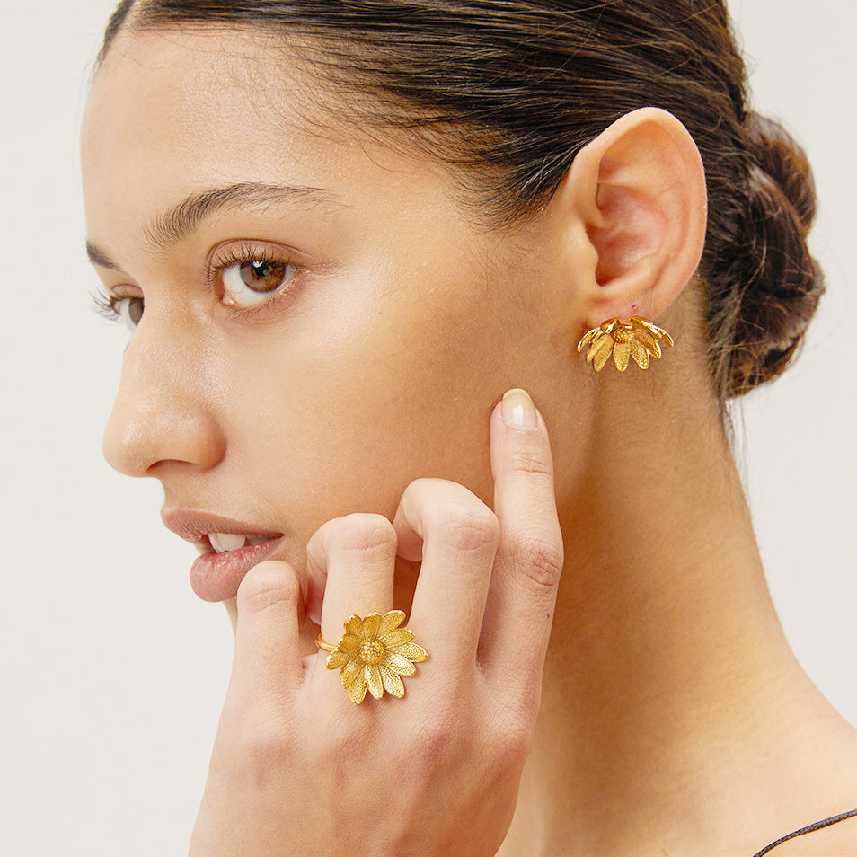 Model showcasing the gold sunflower stud earrings and matching ring