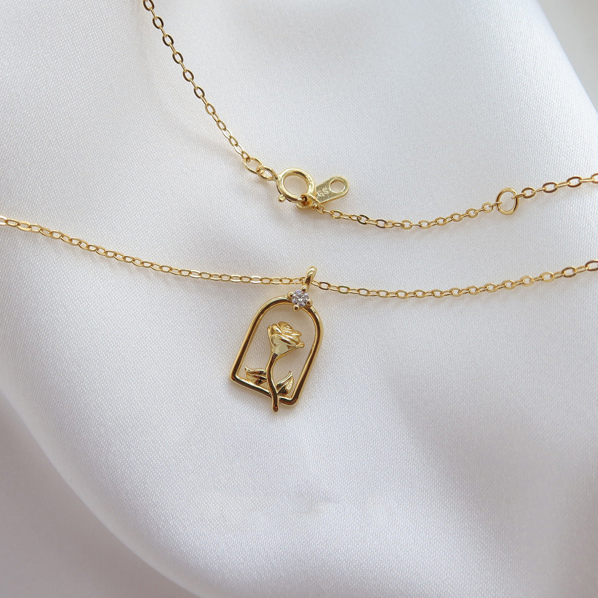 Detailed close-up of the gold enchanted rose pendant with a cubic zirconia stone