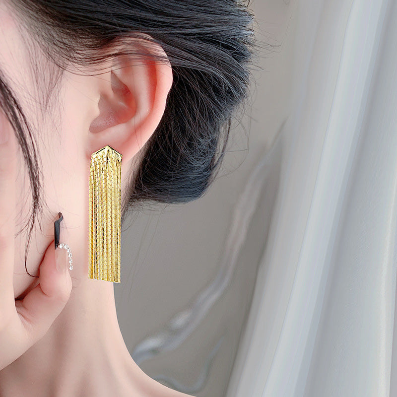 A woman wearing the gold long chain tassel earrings, showcasing their elegant drape.
