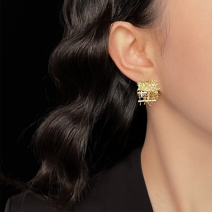 A close-up view of the geometric statement earring, highlighting the textured gold finish and embedded CZ stones.