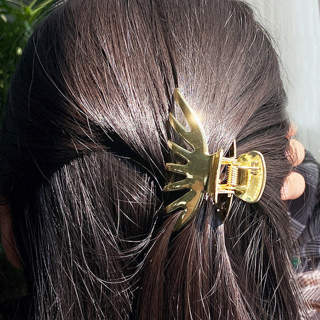 A gold pumpkin-shaped hair clip securing a woman's ponytail.