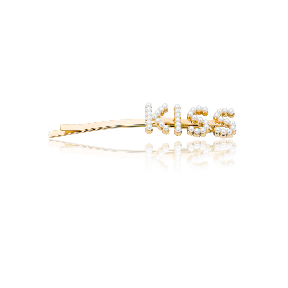 A custom gold hair clip with the word 'KISS' adorned in pearls, demonstrating personalization.