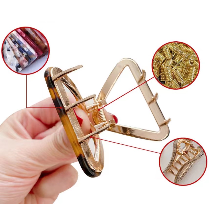 Detailed view of a gold triangle hair clip with a tortoiseshell pattern edge, showing the quality craftsmanship.