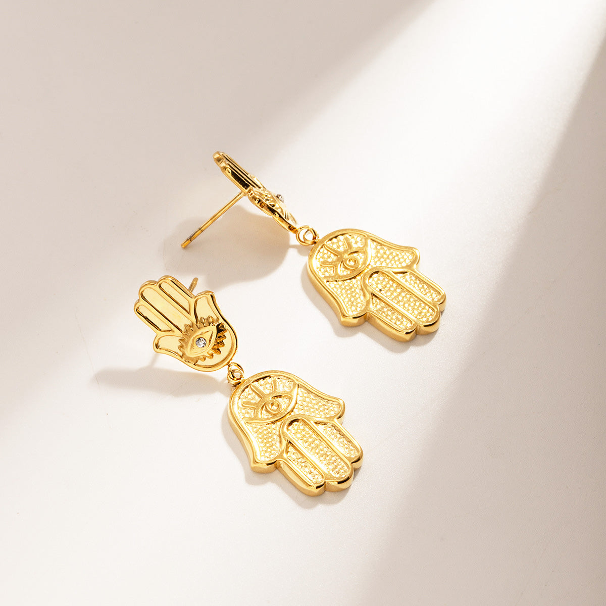 Detailed view of the gold Hamsa hand earring's textured design