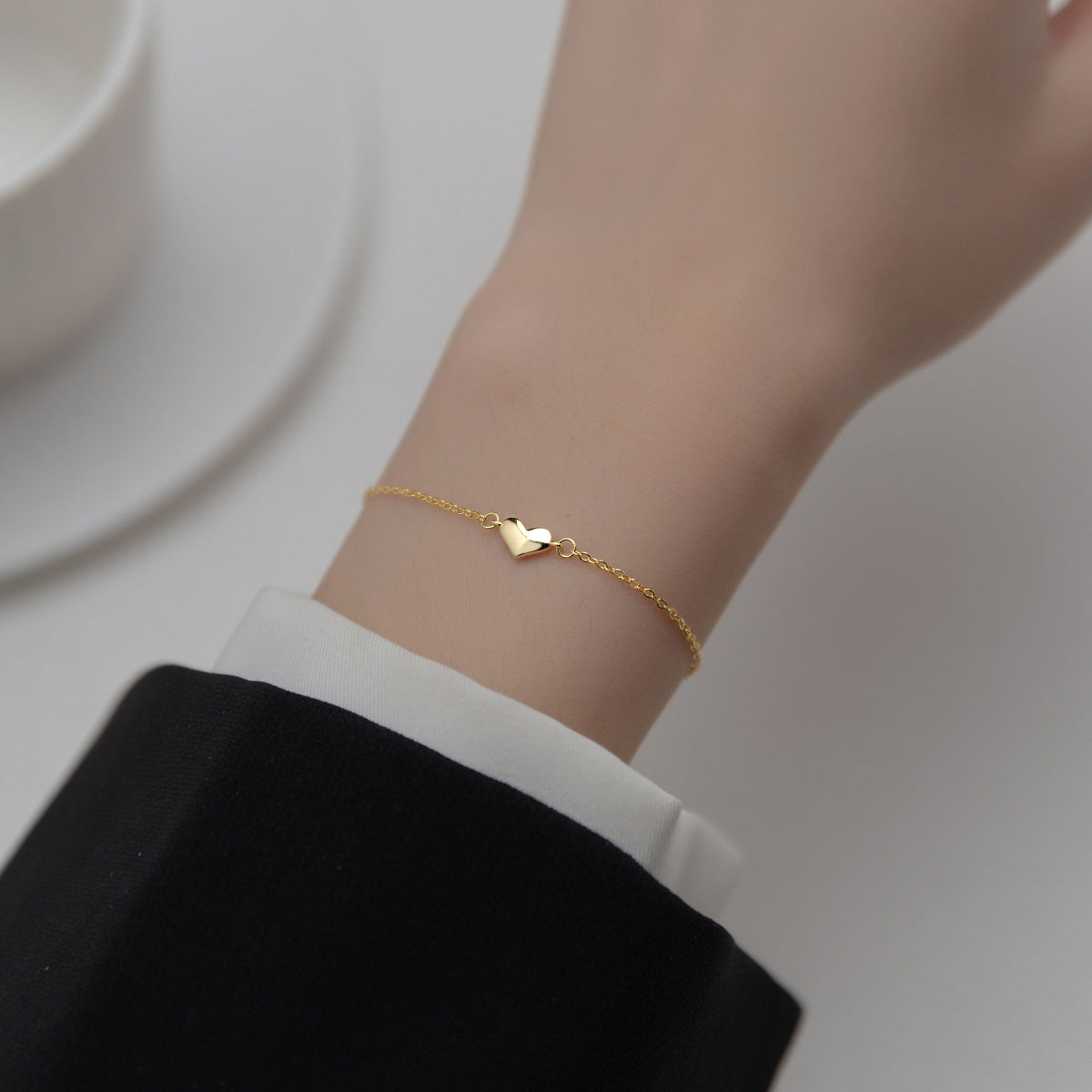 Gold minimalist heart bracelet worn on a wrist