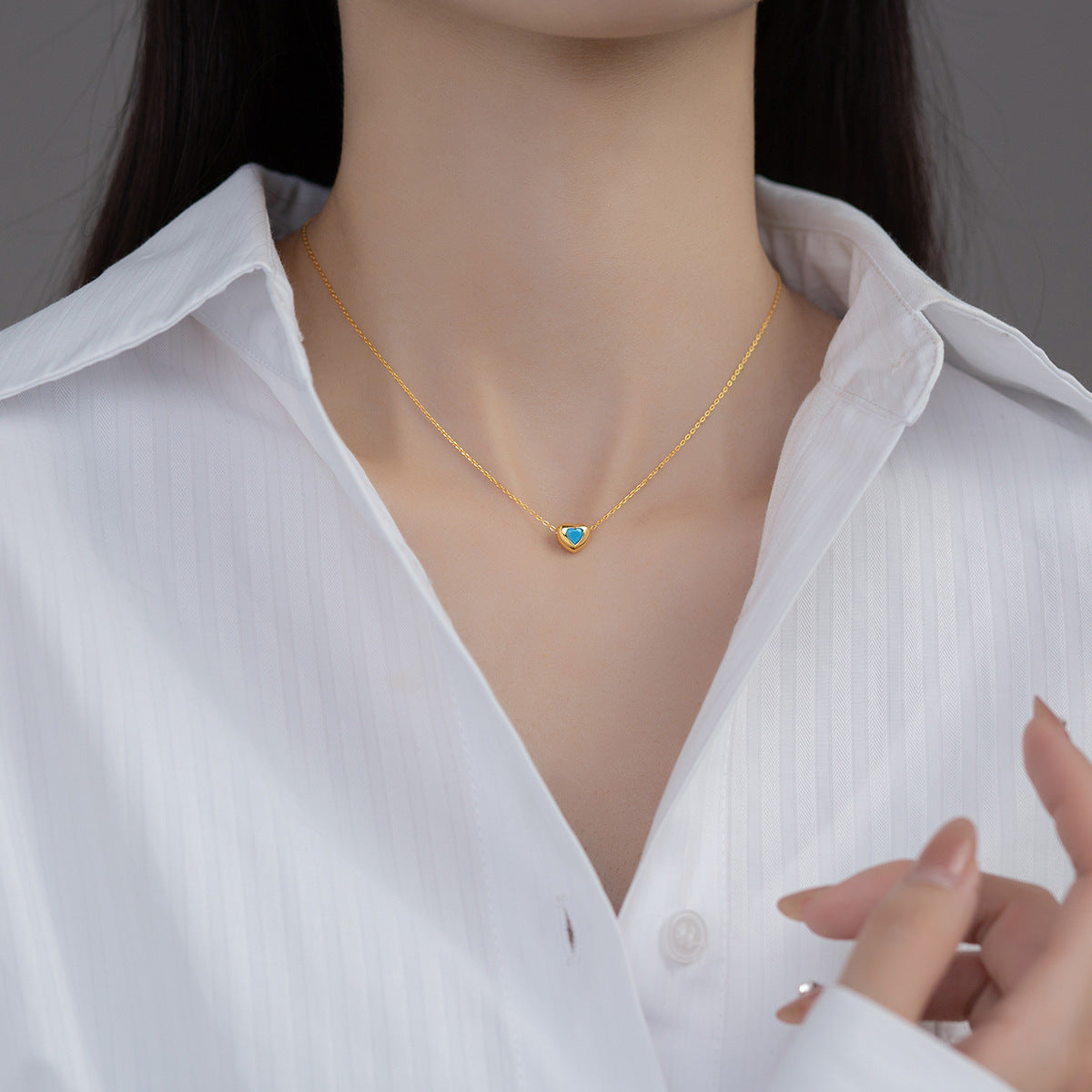 A model wearing the gold 925 sterling silver heart necklace with a blue zircon stone.