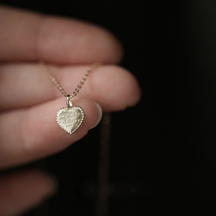 Close-up of the 'love you' engraving on the gold heart pendant.