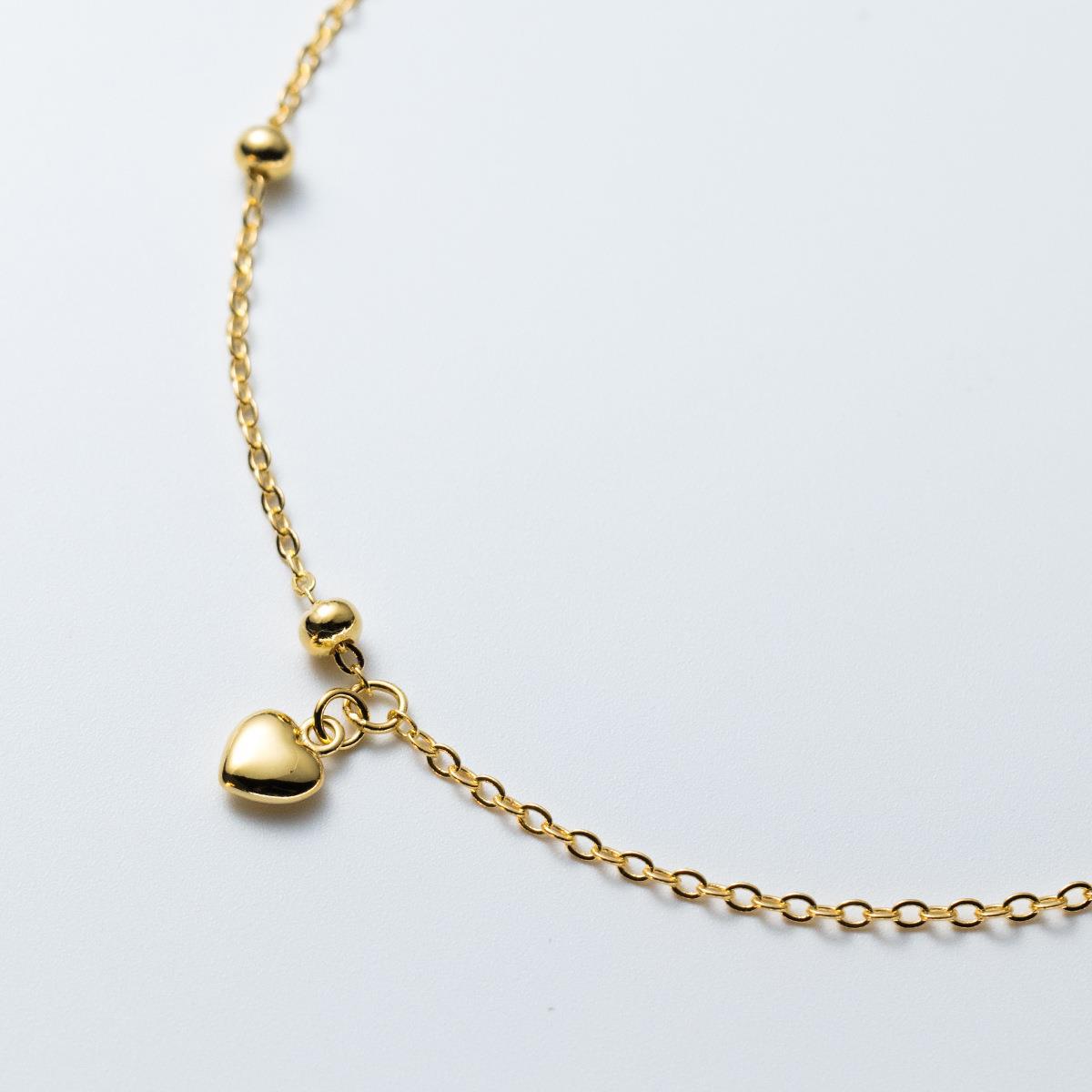 Detailed view of the 18K gold plated heart charm and beads on the sterling silver bracelet.