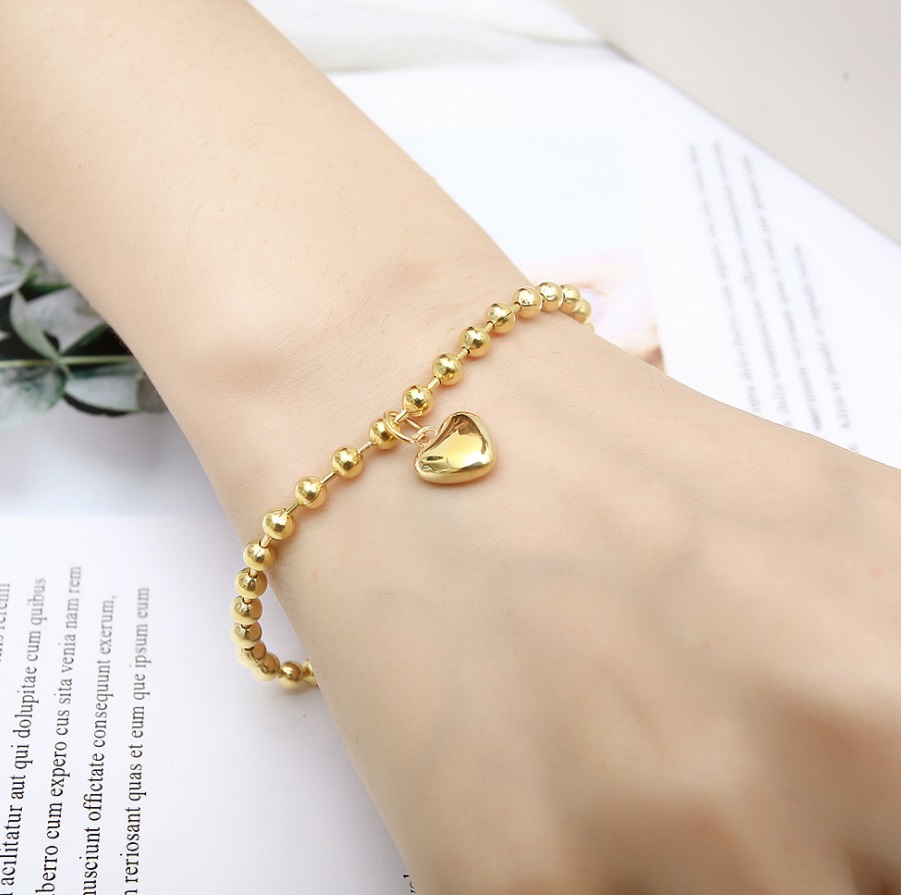A model showcasing the elegant fit of the gold Heart Charm Beaded Bracelet