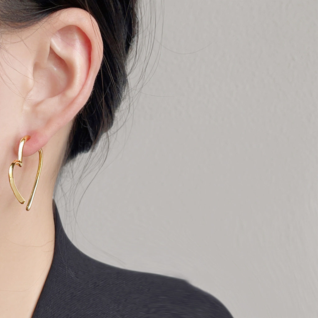 A model wearing the gold geometric heart drop earring, showcasing its elegant design.