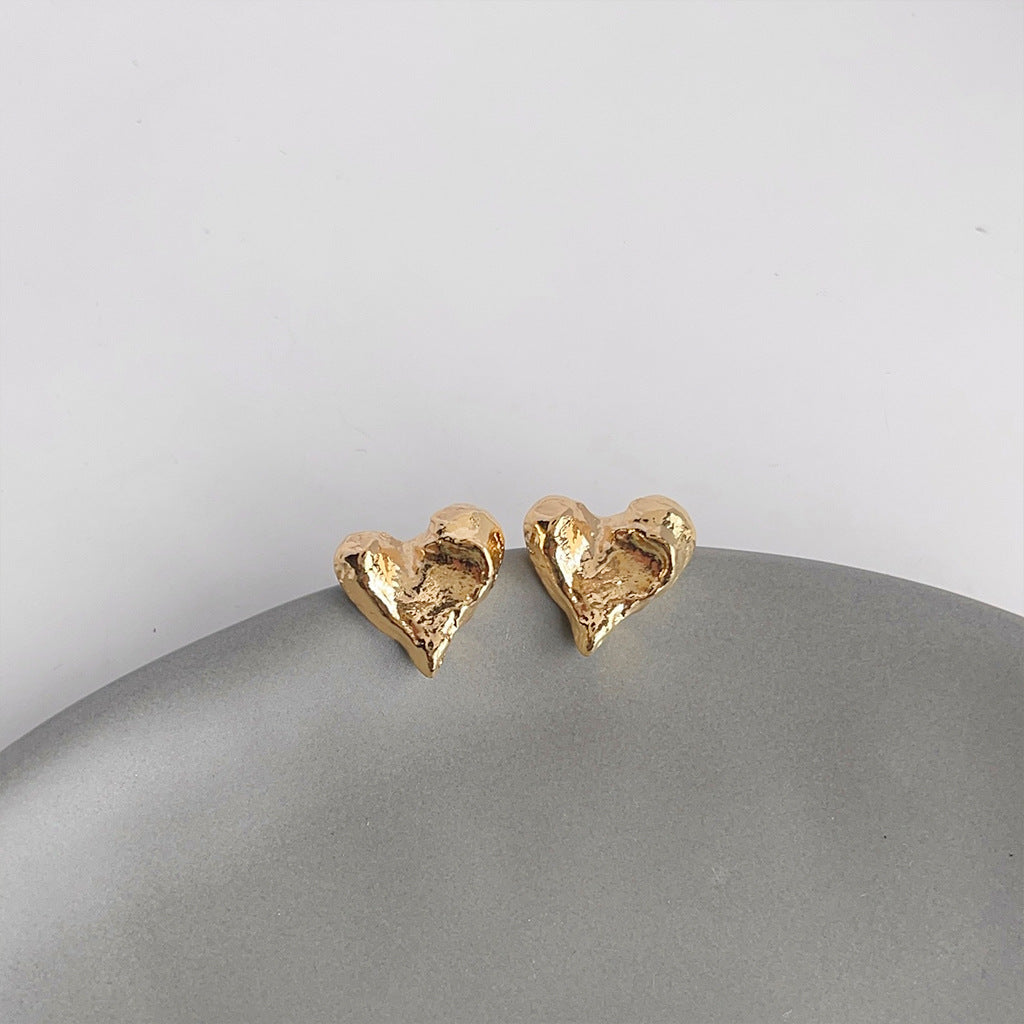Detailed view of the 14K gold plated brass heart earrings with textured finish