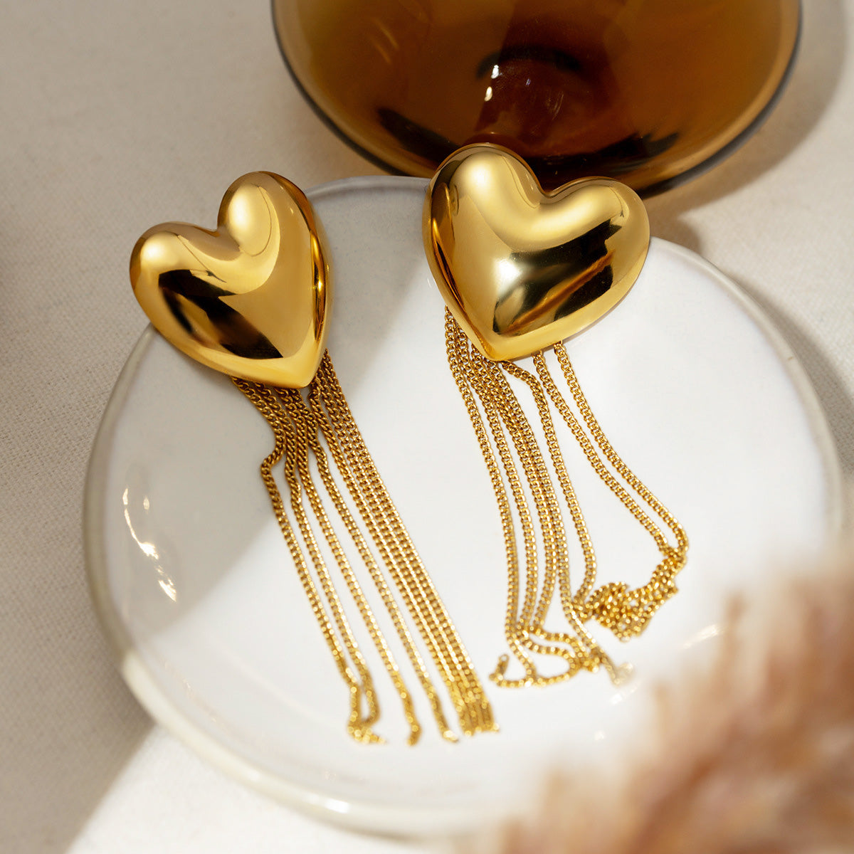 Detailed view of the gold heart tassel earrings showing the chain length