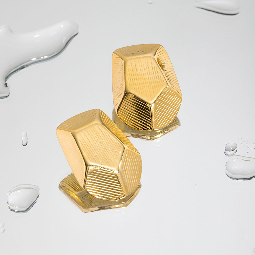 Detailed product shot of the gold geometric pentagon earrings