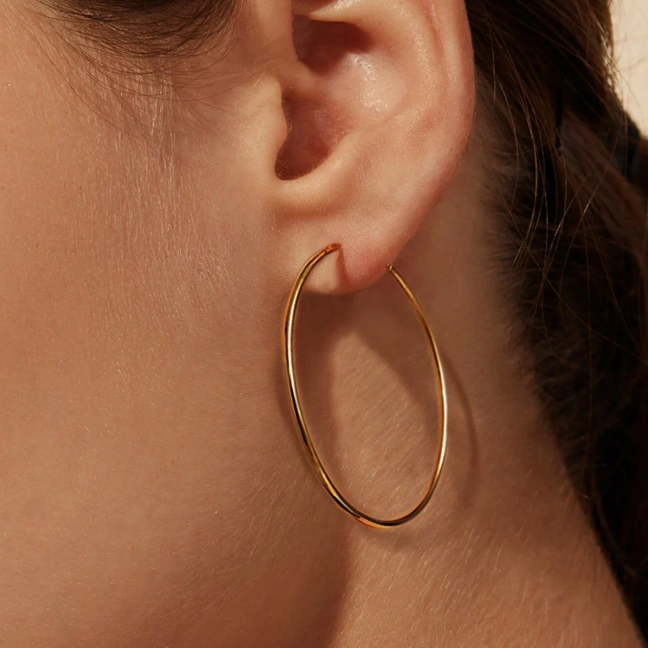 A model wearing the 50mm gold hoop earring to showcase its size and elegant look.