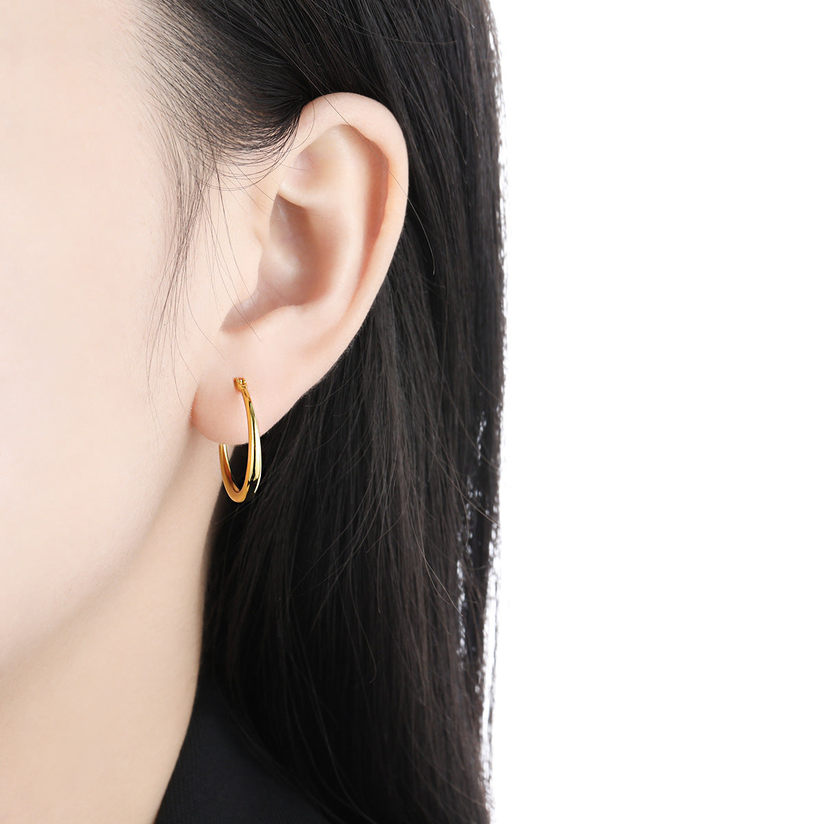 A model showcasing the elegant 20mm 18K gold plated hoop earring.