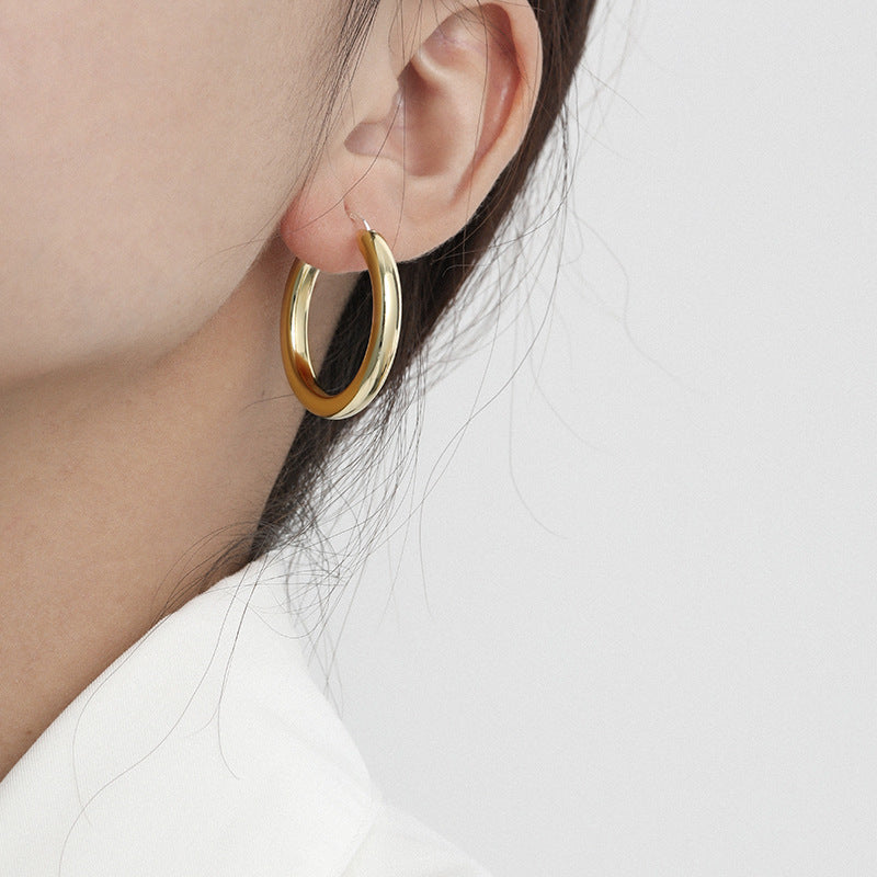 A model showcasing the chic look of the gold thick hoop earrings.