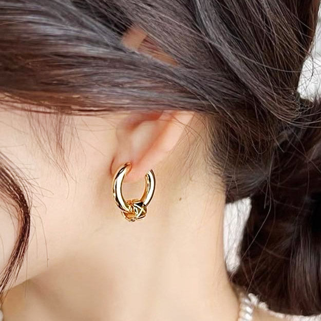 A woman wearing a vintage gold-plated huggie hoop earring.