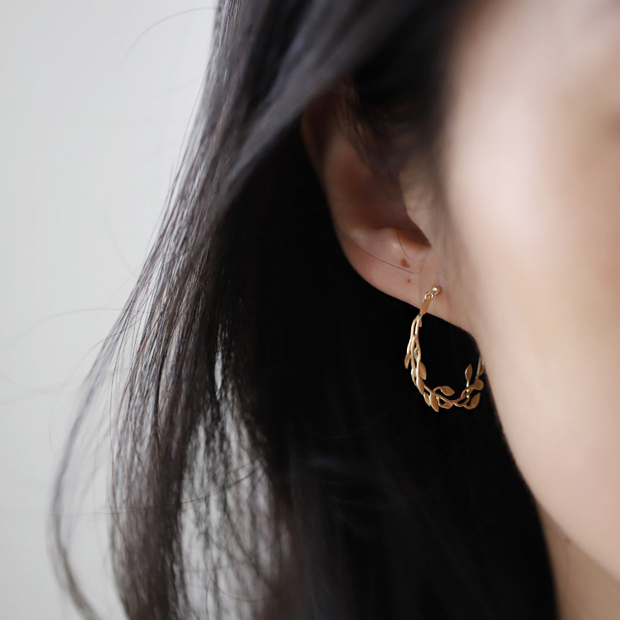 A model wearing the gold leaf stud earrings to show scale and style.