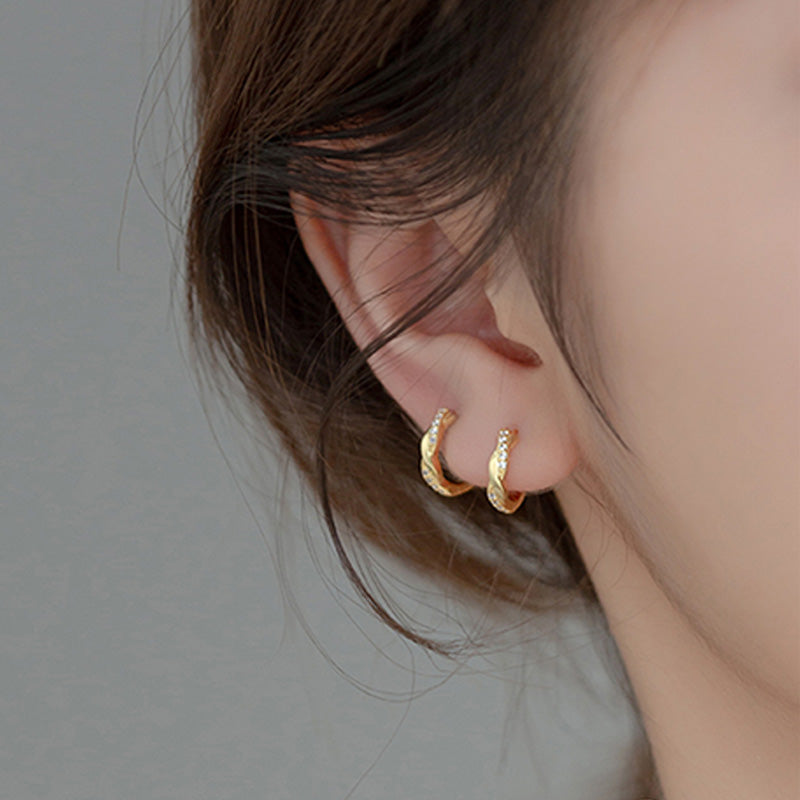 A woman wearing the gold-plated Elegant Twist zircon earrings, showcasing their sparkle.